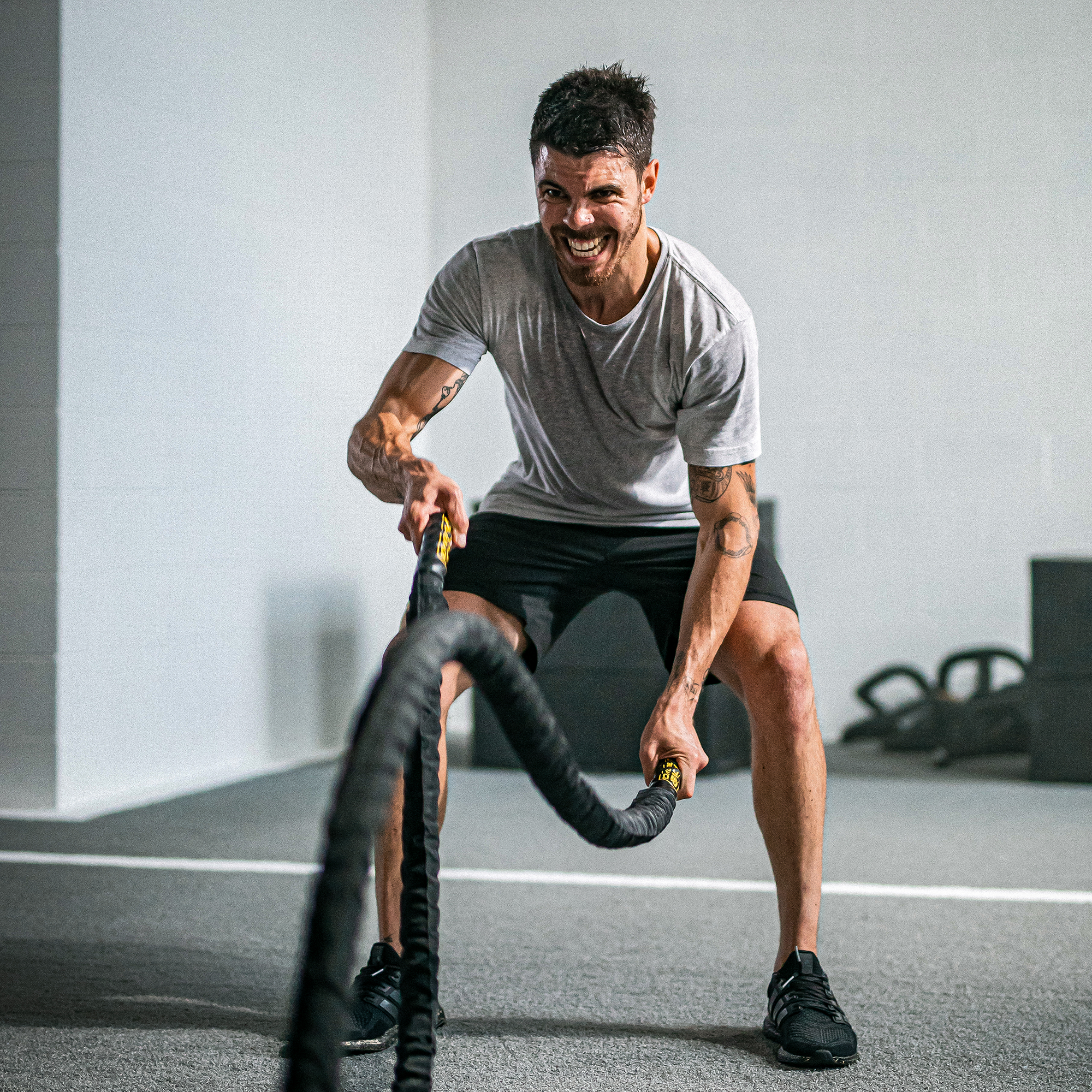 man in a gym doing battling ropes exercise
